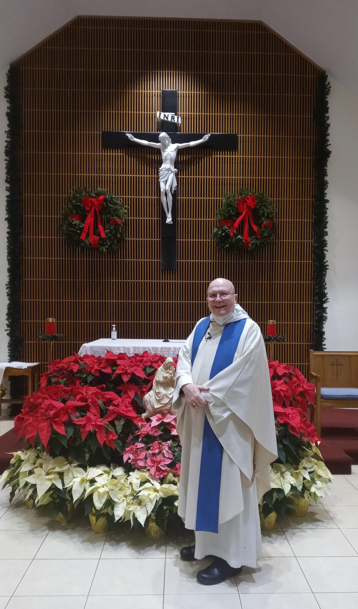 Father Hugh in front of Christmas Decorations